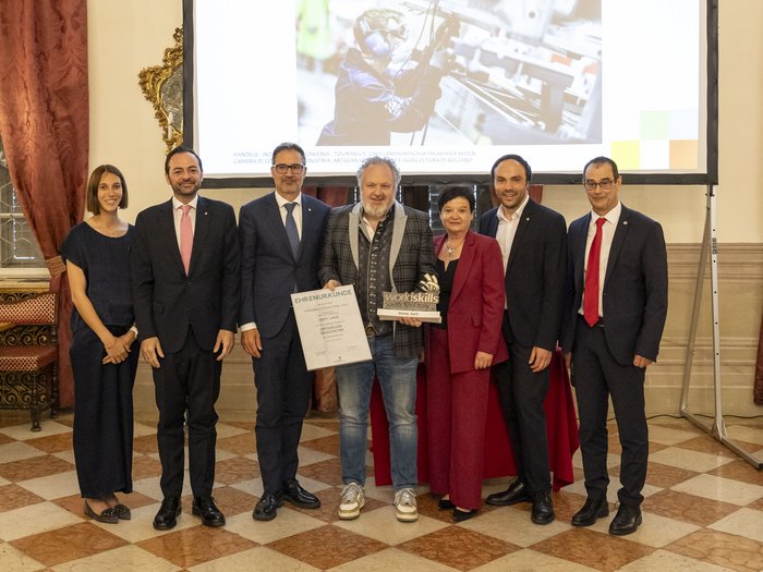 30 Jahre WorldSkills South Tyrol, Italy: die Erfolgsgeschichte der Berufsmeisterschaften Gruppe von sieben Personen bei einer Auszeichnung mit Urkunde und Trophäe