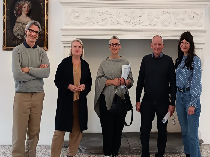 Finanziamenti per il restauro di edifici sotto tutela: nuovi regolamenti e importanti modifiche Cinque persone in piedi davanti a un camino bianco decorato con un quadro sul muro