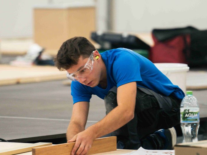 EuroSkills 2023: adesso bisogna concentrarsi! Uomo con occhiali protettivi lavora con legno in un interno