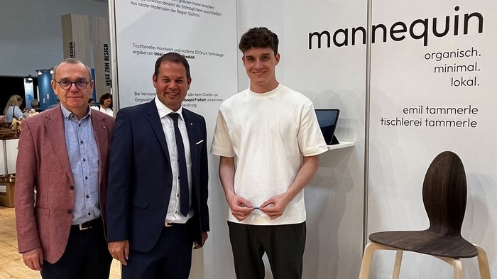 lvh-Direktor Thomas Pardeller, lvh-Vizepräsident Hannes Mussak und Emil Tammerle © lvh.apa Drei Männer vor Messestand mit modernem Stuhl aus Holz