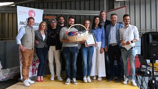 News Gruppe von zehn Personen bei Preisverleihung mit Geschenkekorb und Urkunde