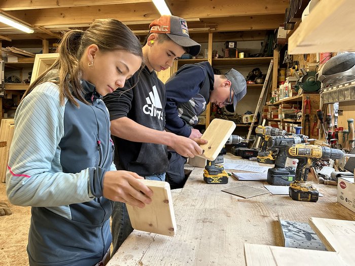 Handwerk hautnah erleben: Die Sarner Mittelschüler/innen entdecken ihre berufliche Zukunft Drei Jugendliche arbeiten in einer Holzwerkstatt an Holzstücken