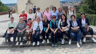 News Gruppe von Frauen sitzt vor einer historischen Mauer mit einer Stadt im Hintergrund