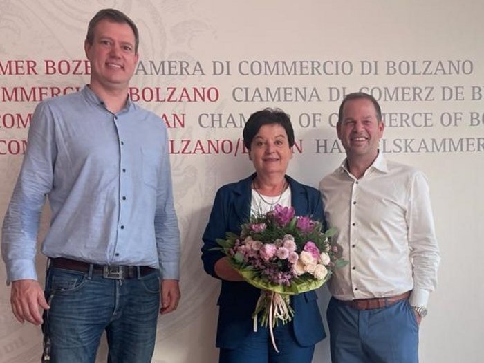 Drei Frauen aus dem Handwerk erobern die Führungsebene Drei Personen stehen vor der Kammer der Wirtschaft von Bozen, Frau hält Blumenstrauß