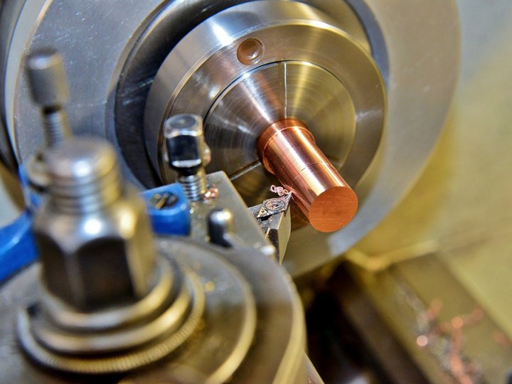 Maschinenbaumechaniker und Werkzeugmacher Drehbank bearbeitet ein rundes Kupfermetallteil