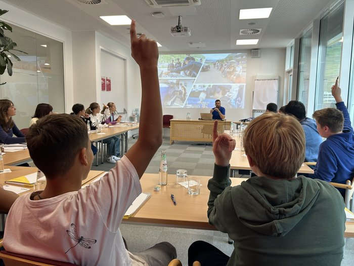 Professioni pratiche nell'artigianato e nel settore alberghiero al centro dell'attenzione Studenti alzano la mano in aula durante una presentazione