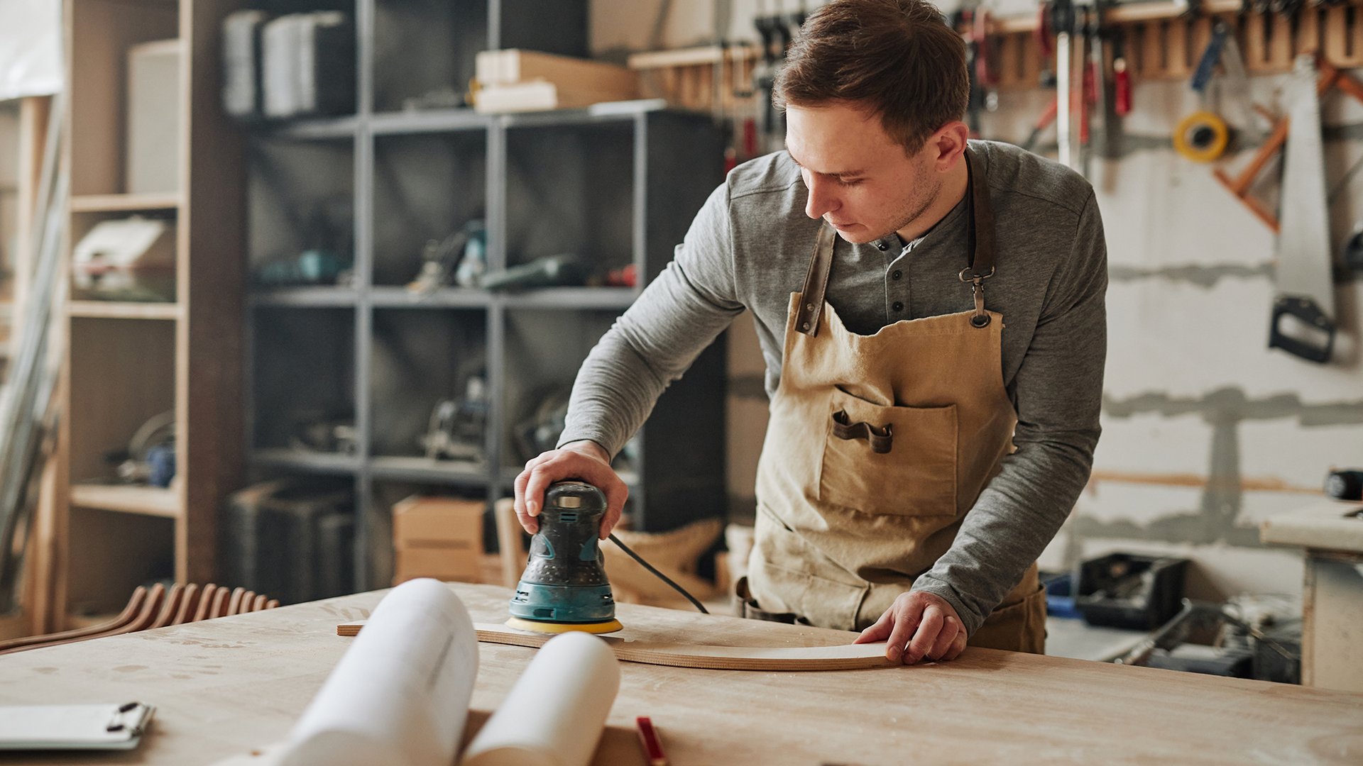 Home Uomo che leviga un pezzo di legno in una bottega