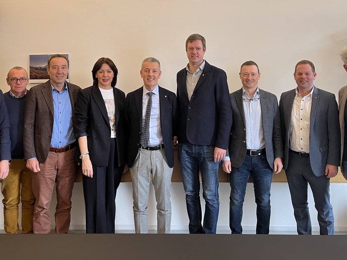 Zukunft des Handwerks: Strategische Gespräche zwischen lvh und Landesrat Peter Brunner Zehn Geschäftsleute stehen in einem Büro vor einer Wand und lächeln