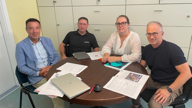 Home Quattro persone sedute intorno a un tavolo rotondo con documenti e laptop in ufficio