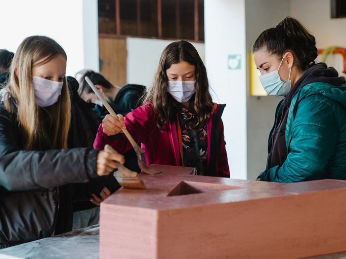 Junghandwerker Ritten besuchen Mittelschüler Jugendliche mit Masken bemalen einen großen roten Buchstaben aus Holz in Innenraum