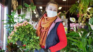 News Frau mit Maske hält Blumenstrauß in einer Blumenhandlung