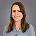 Workshops Porträt einer lächelnden jungen Frau mit braunen Haaren vor grauem Hintergrund