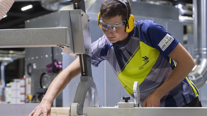 WorldSkills 2022: iniziate le prime competizioni Giovane uomo usa un seghetto da tavolo con occhiali e cuffie protettive