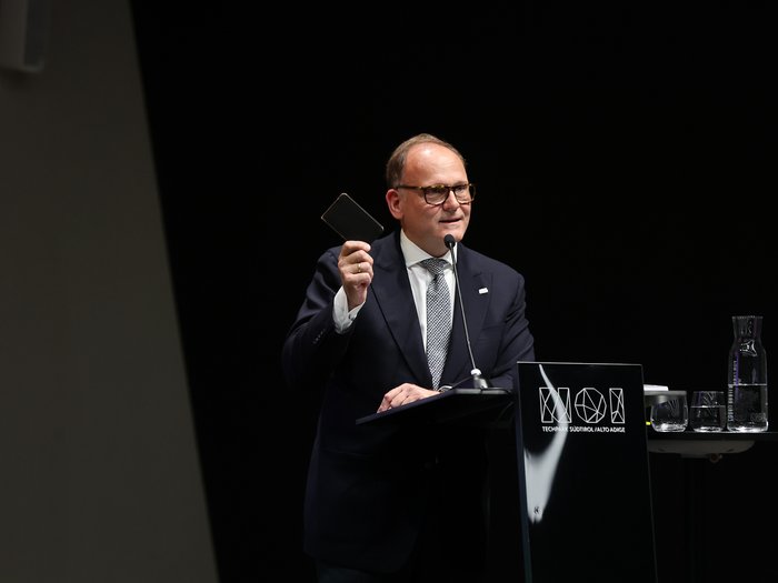 Assemblea generale del SWR-EA 2025 - La nostra competitività è in pericolo? Uomo in abito tiene un dispositivo e parla al microfono da un podio