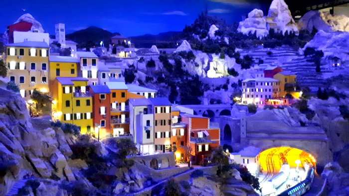 Die Althandwerker besuchen Hamburg Modellbahnlandschaft mit bunten Häusern und beleuchtetem Tunnel in den Bergen bei Nacht