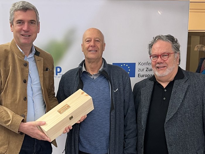 Althandwerker/innen im Herzen der Europäischen Union Drei Männer stehen vor einer Wand und halten eine Holzkiste in einem Büro