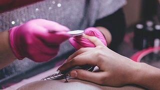 News Maniküre mit rosa Handschuhen bei der Nagelpflege