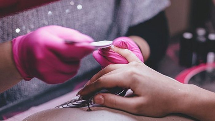 Bilaterale Körperschaft unterstützt Körperpflegeberufe Maniküre mit rosa Handschuhen bei der Nagelpflege