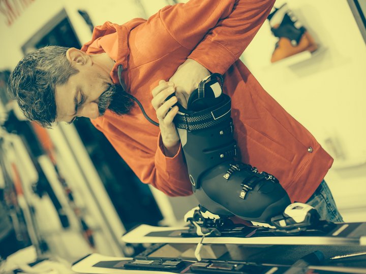Tecnici manutenzione articoli sportivi Uomo regola scarponi da sci su sci in un negozio sportivo