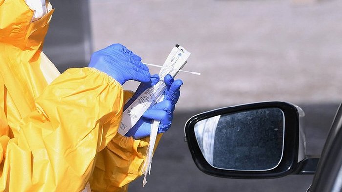 Betriebe nutzen Testangebot in Bozen Person in Schutzanzug und Handschuhen bereitet Abstrich für Covid-Test im Auto vor