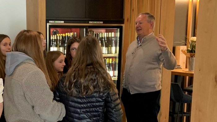 Handwerk gemeinsam mit Hotel- und Gastgewerbe zu Besuch im Untervinschgau Gruppe Jugendlicher hört einem Mann in modernem Raum zu