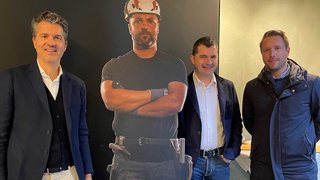 News Drei Männer stehen neben einer Baustellenhelden-Pappfigur mit Helm und Werkzeug