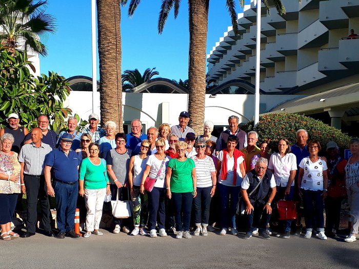 Althandwerker Rhodos 2022 © lvh.apa Große Gruppe älterer Menschen vor einem Hotel mit Palmen bei Sonnenschein