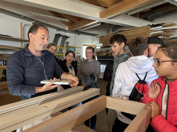 Wissen entdecken: Die Welt der praktischen Berufe Handwerker zeigt Kindern Holzarbeiten in Werkstatt