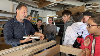 News Handwerker zeigt Kindern Holzarbeiten in Werkstatt