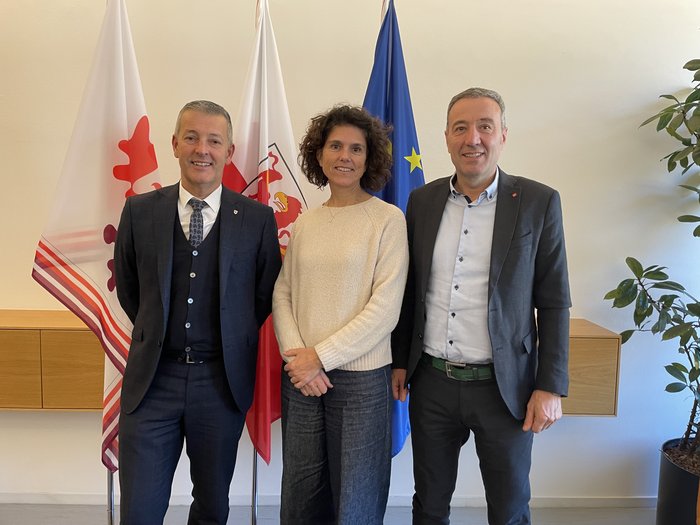 Smaltimento degli pneumatici fuori uso: le officine altoatesine chiedono soluzioni Tre persone davanti a tre bandiere, sorridenti e vestite formalmente