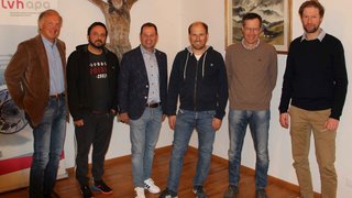 News Sechs Männer stehen in einem Raum mit einer Kreuzigungsskulptur und einem Bild an der Wand