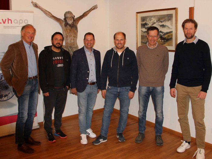 Das Kunsthandwerk „begeistert“ Sechs Männer stehen in einem Raum mit einer Kreuzigungsskulptur und einem Bild an der Wand