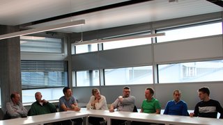 News Menschen sitzen an einem U-förmigen Tisch in einem modernen Besprechungsraum