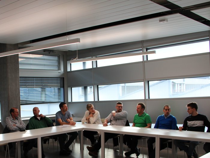 Rückblick und Zukunftsplanung im Zeichen der Innovation Menschen sitzen an einem U-förmigen Tisch in einem modernen Besprechungsraum