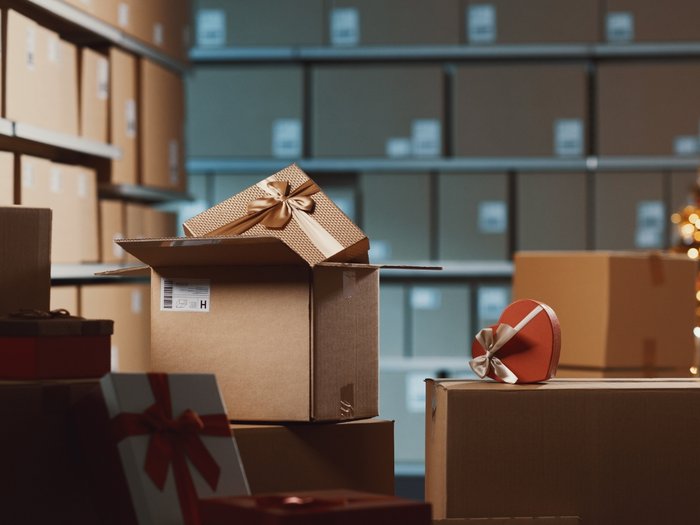 „Kein Interesse an gelenkter Lieferverzögerung“ Weihnachtsgeschenke in Kartons im Lager mit Weihnachtsbaum im Hintergrund.