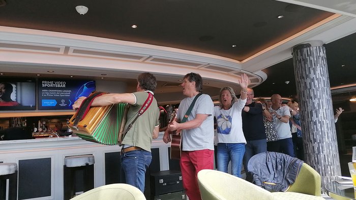 Artigiani anziani in crociera Gruppo di persone che ballano e suonano musica in un bar con fisarmonica e chitarra
