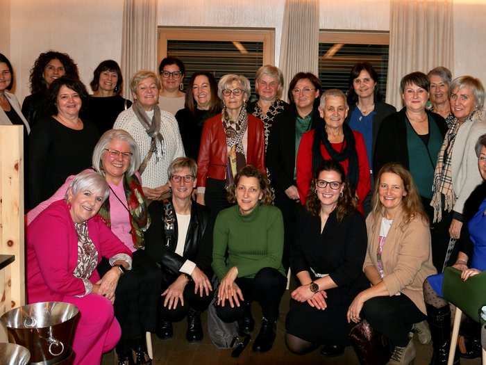 Weihnachtsessen - Bezirk Burggrafenamt Gruppenfoto von 22 Frauen in einem Innenraum vor einem Fenster mit Vorhängen