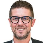Tischler Porträt eines lächelnden Mannes mit Brille und kurzem Haar vor weißem Hintergrund