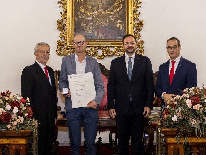 Südtiroler Wirtschaftspreis 2024 Vier Männer bei einer Ehrungszeremonie, einer hält Urkunde und Medaille