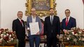 Südtiroler Wirtschaftspreis 2024 Vier Männer bei einer Ehrungszeremonie, einer hält Urkunde und Medaille