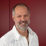 Bozen Land Porträt eines lächelnden Mannes vor rotem Hintergrund