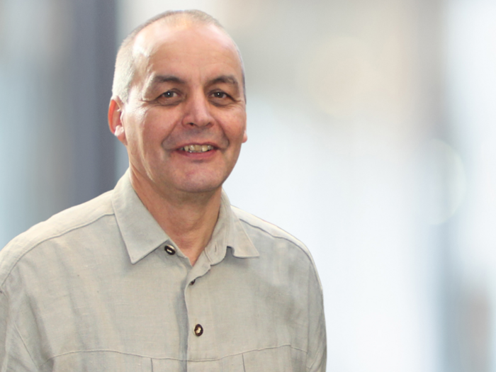 Holzbaufonds: Klimaschutz trifft Handwerk Mann mit grauem Hemd lächelnd vor unscharfem Hintergrund