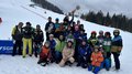 Handwerker/innen tauschen Werkzeuge gegen Skier und Rodel Gruppenfoto von Skifahrern und Trainern mit Trophäen im Schnee vor einem Skihang