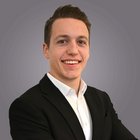 Donne nell‘artigianato Giovane uomo con giacca nera e camicia bianca sorride su sfondo grigio