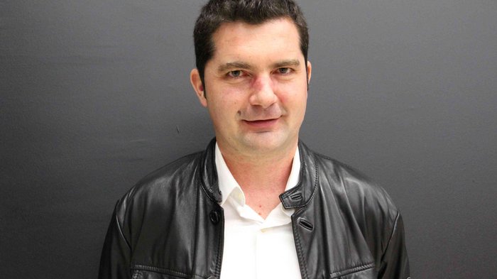 Thema: Generationenwechsel Porträt eines Mannes mit schwarzer Lederjacke und weißem Hemd vor grauem Hintergrund