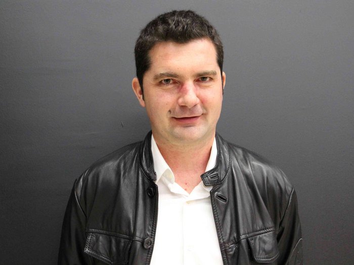 Thema: Generationenwechsel Porträt eines Mannes mit schwarzer Lederjacke und weißem Hemd vor grauem Hintergrund