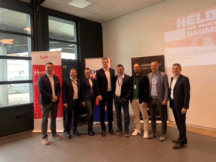 Jahresversammlung der Baumeister/innen und Maurer/innen: Ein Forum für Austausch und Innovation Gruppe von acht Personen bei einer Veranstaltung vor Bannern im Innenraum