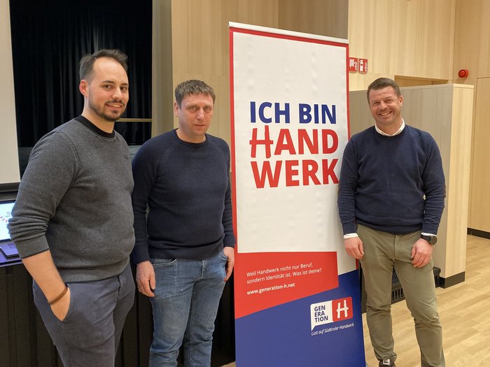 San Leonardo e l’artigianato: progetti futuri e prospettive solide per il territorio Tre uomini in piedi davanti a uno striscione con la scritta Ich bin Handwerk