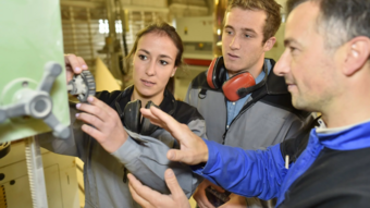 Home Tre persone lavorano insieme su un controllo macchina in un'officina