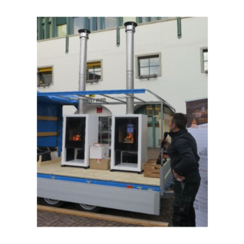 Hafner Mann betrachtet zwei Holzöfen auf einem Anhänger vor einem Gebäude